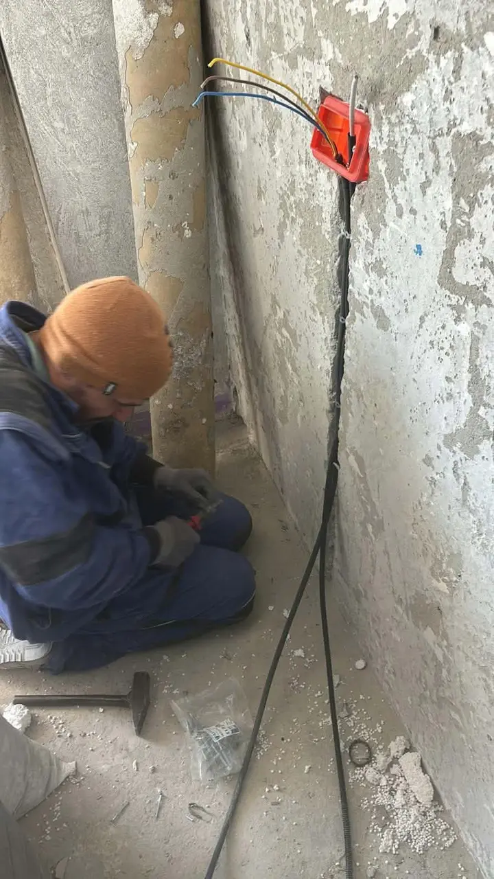 Cablarea unei doze roșii dintr-un perete, cu ciocan și dibluri pe pardoseală