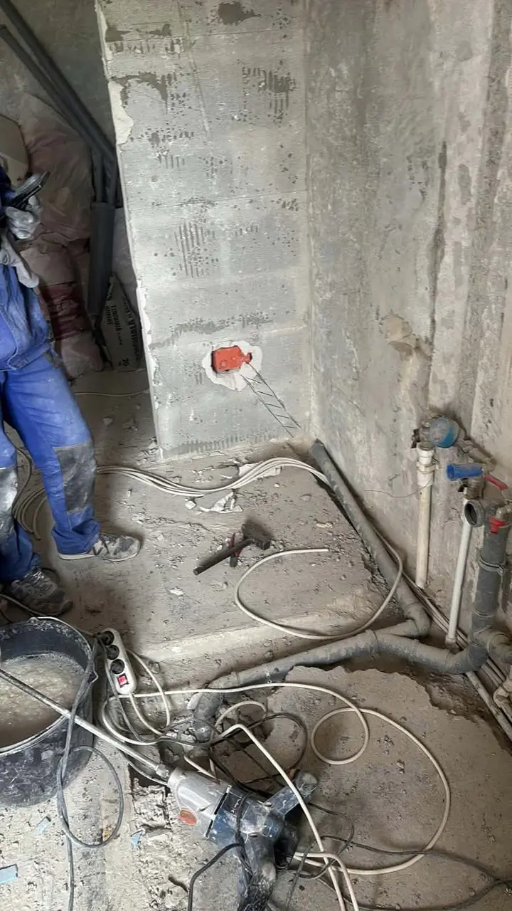 Doză roșie montată în perete, lângă țevi și un rotopercutor